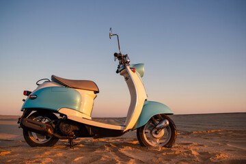 Retro blue scooter at sunset in the golden sand of the Namib Desert