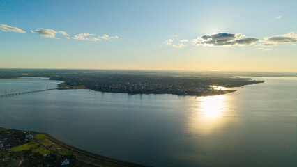 Silhouette of Posadas city during a sunset over the Paraná River, with the vibrant colors of the sky reflecting on the water.