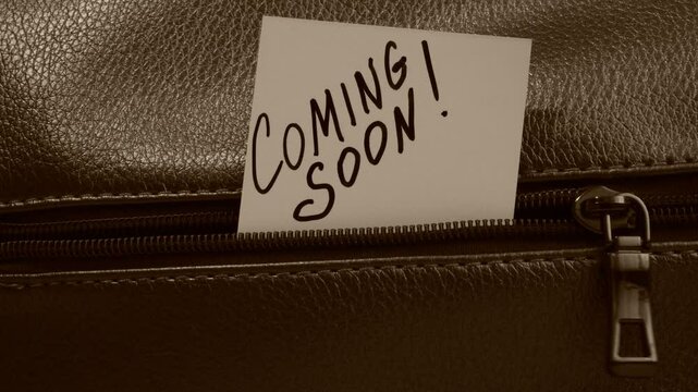 Text Coming Soon on paper. Close up of zip on dark textured leather. Grunge style