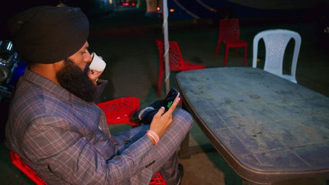 Bearded man enjoys coffee looking mobile screen