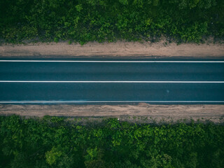 Aerial view of an empty road in lush green forest landscape