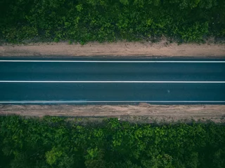 Fotobehang Bospad Aerial view of an empty road in lush green forest landscape  © Parilov