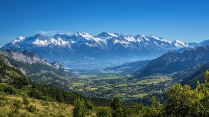 Fototapeta premium A breathtaking view of snow-capped mountains under a clear blue sky, with a valley below