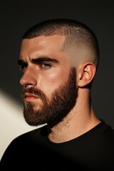 Fototapeta premium portrait of man with precision-cut beard and buzz haircut under directional studio light