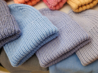 A row of knit hats in various colors, including blue, pink, and yellow