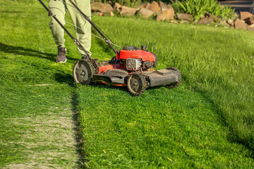 Close-up of a red lawn mower cutting grass with visible mowing path