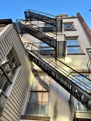 Naklejka premium Fire escapes on beige building with windows in Manhattan