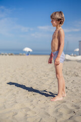 Young boy standing straight with a blue sky in the background © Cavan