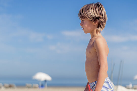 Side view of a young boy standing on the beach