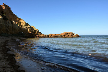 Rocky outcrop illuminated by the sun at Melbourne's Red Bluff, seen from across the water early in the morning