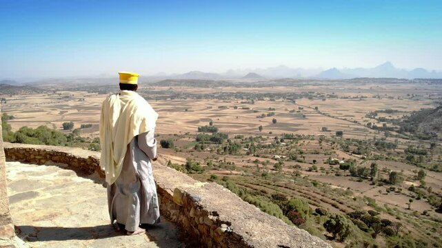 African Priest Watching the wide Desert of Ethiopia
Unidentified Ethiopian Priest In traditional Clothing Looking on Wide Desert Mountains

