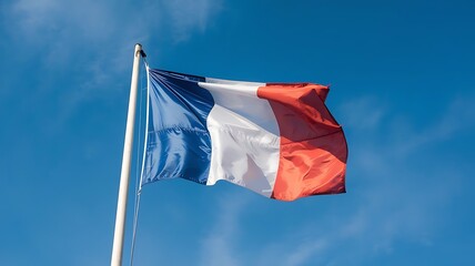 French flag waving against a clear blue sky, showcasing national colors and symbol of France's heritage