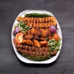 Mixed grill large platter with tomato, onion and green chilli in a plate