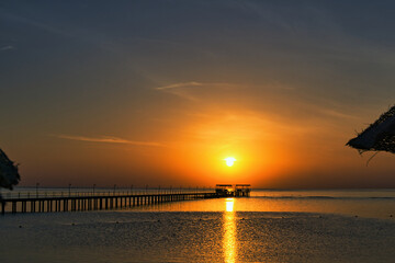Obraz premium Fantastic sunrise in Marsa Alam over the Red Sea. visible palm trees, beach umbrellas, typical hotel buildings. Egypt, Marsa Alam 2024