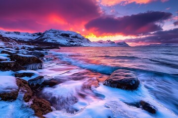 Fototapeta premium Stunning Rocky Coastline Covered in Snow with Gentle Waves Lapping Against the Shore Under a Vibrant Sunset Sky