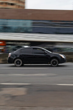 Black Sedan cruising city traffic, Nissan Sentra in urban cenario