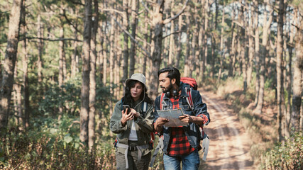 Travelers hiking through a forest with backpacks, exploring the wilderness and taking in the sights of nature as they walk.