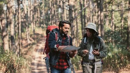 Travelers hiking through a forest with backpacks, exploring the wilderness and taking in the sights of nature as they walk.