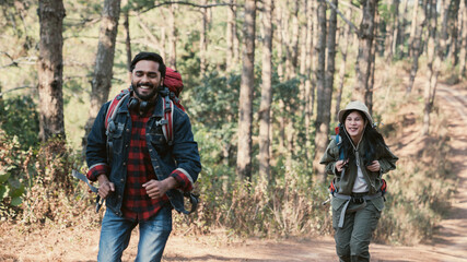 Travelers hiking through a forest with backpacks, exploring the wilderness and taking in the sights of nature as they walk.