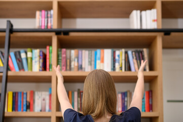Wyciągnięte ręce w stronę biblioteczki z książkami, wiedza i  wykształcenie koncept © Paweł Kacperek