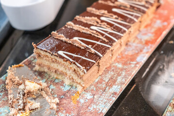 A chocolate cake with white frosting is cut into pieces