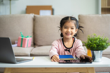 Naklejka premium Attentive daughter writing in notebook while sitting at desk and doing homework.