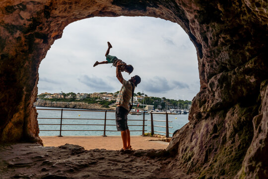 Father lifting son in coves del drac, mallorca, spain