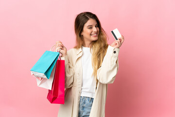 Young woman with shopping bag isolated on pink background holding shopping bags and a credit card