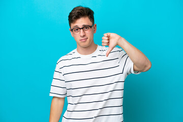 Young handsome Brazilian man isolated on blue background showing thumb down with negative expression