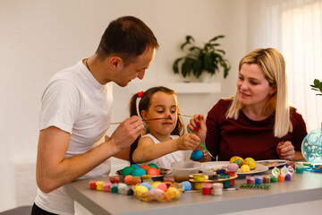 Obraz premium Happy family painting Easter eggs at table in kitchen.