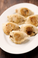 Dumplings with potato and cottage cheese stuffing (pierogi). Wooden background. Close up. 