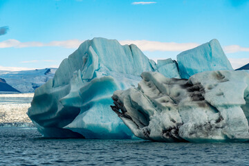 Blue icebergs float peacefully in the Jökulsárlón glacier lagoon in Iceland, with scenic mountains rising in the background