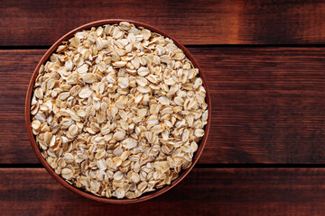 Ceramic Bowl with Raw Oat Flakes on Brown Wooden Table, Healthy Breakfast Ingredients, Top View, Copy Space