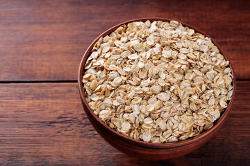 Ceramic Bowl with Raw Oat Flakes on Brown Wooden Table, Healthy Breakfast Ingredients, Top View, Copy Space