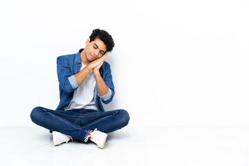 Venezuelan man sitting on the floor making sleep gesture in dorable expression