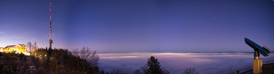 Panorama of the city of Zurich from the Uetliberg with sea of ​​fog at night with television tower and telescope