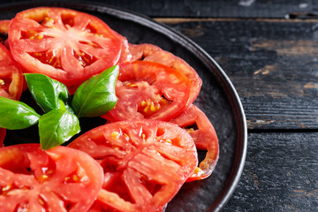 Organic Tomato Slices and Basil Leaves on Black Plate, Italian and Mediterranean Cuisine, Close-Up