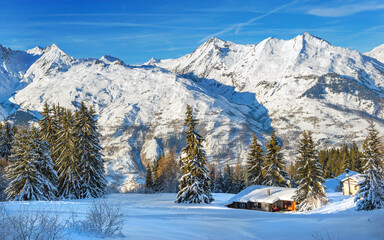 winter landscape in mountain covered with snow under blue sky and chalet at the foot of mountains in a ski resort in tarentaise - france