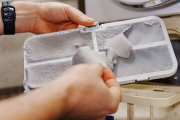 cleaning the filter in the dryer. Modern household appliances for washing and drying clothes. Care...