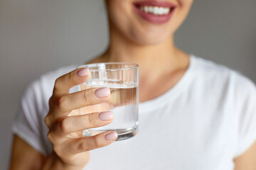 Woman hand holding glass of clear water give to camera smiling selective close up focus. Concept of...