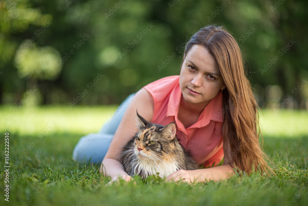 Wall mural Portrait of a young beautiful long-haired girl, in light clothes in the summer, in the park with a cat.