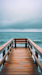 Obraz premium Weathered wooden pier stretches out over the ocean, ending in a simple bench perfectly placed for gazing across the vast expanse of tranquil water.