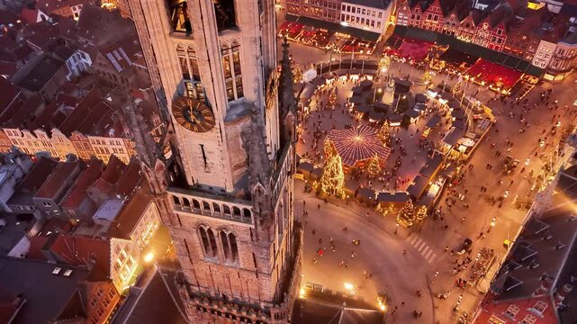 Bruges evening view with bustling Christmas market and iconic bell tower
