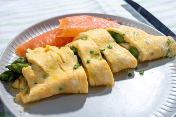 Chicken eggs omelette stuffed with green asparagus with smoked salmon fish, french cuisine, close up