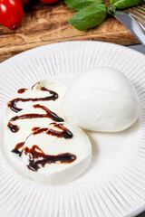 Tasty italian food, fresh white buffalo mozzarella soft cheese balls from Campania served with balsamic vinegar from Modena close up