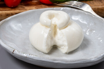 Cheese collection, eating of fresh soft white burrata cheese ball made from mozzarella and cream from Apulia, Italy, close up