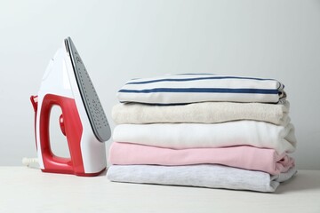 Stack of clothes and iron on table