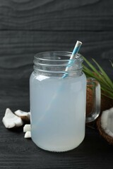 Mason jar with coconut water with nuts on wooden table
