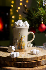 Cup of hot cocoa with marshmallow and cinnamon stick surrounded by spruce branches. Cozy seasonal holidays