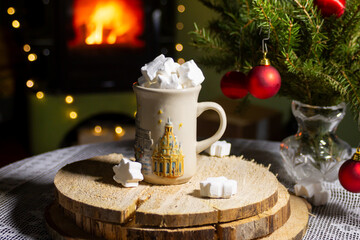 Cup of hot cocoa with marshmallow and cinnamon stick surrounded by spruce branches. Cozy seasonal holidays